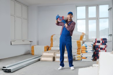 Photo of Construction worker with new building materials in room prepared for renovation