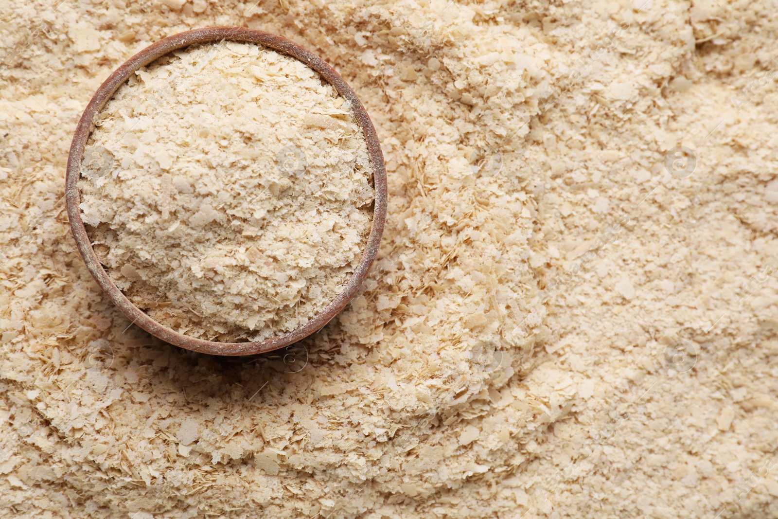 Photo of Wooden bowl of brewer`s yeast on flakes, top view