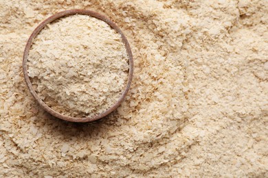 Photo of Wooden bowl of brewer`s yeast on flakes, top view