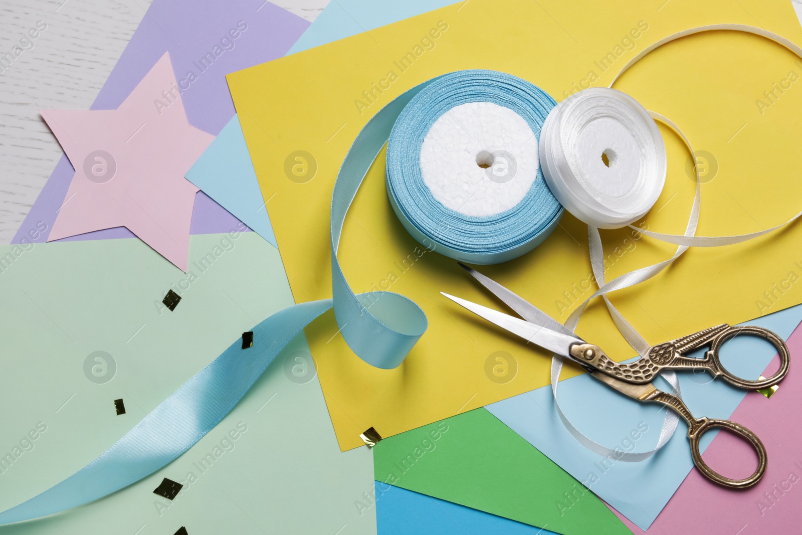 Photo of Pair of scissors with ribbons and colorful paper sheets on white wooden table, flat lay