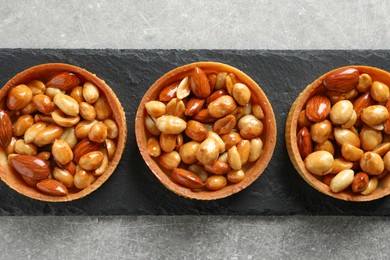 Photo of Tartlets with caramelized nuts on light grey table, top view. Tasty dessert