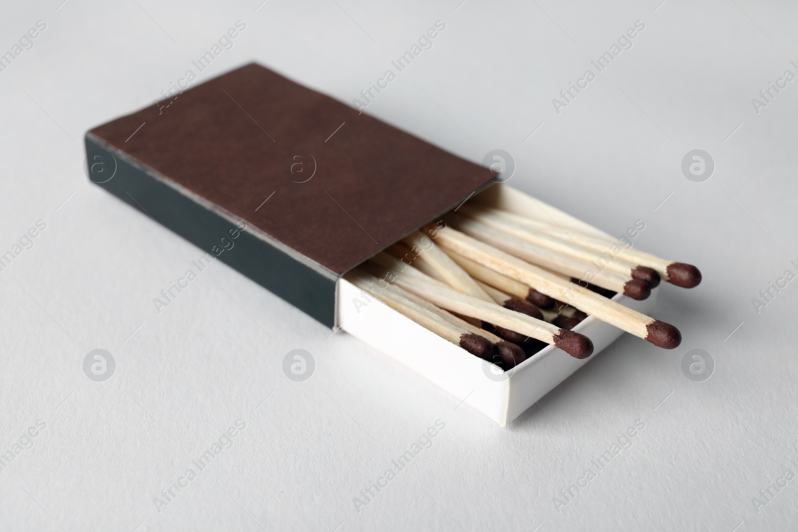 Photo of Cardboard box with matches on light background. Space for design