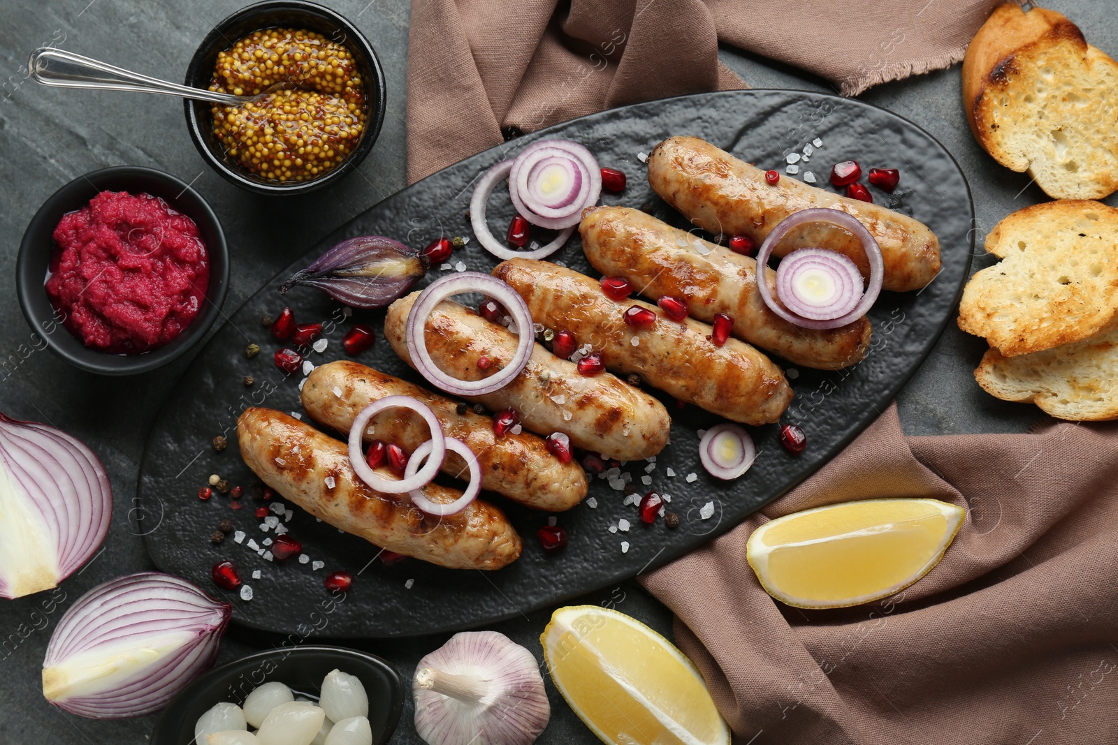 Photo of Tasty grilled sausages served on grey table, flat lay