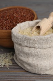 Photo of Bag and bowl with different sorts of rice on wooden table, closeup