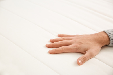 Photo of Man checking mattress firmness, closeup. Space for text