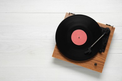 Turntable with vinyl record on white wooden background, top view. Space for text