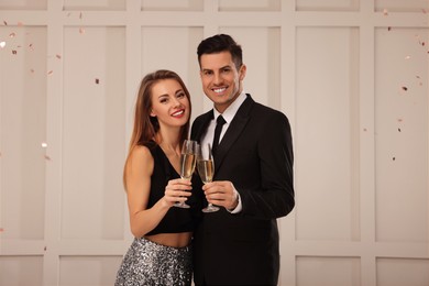 Photo of Happy couple with glasses of sparkling wine celebrating New Year indoors