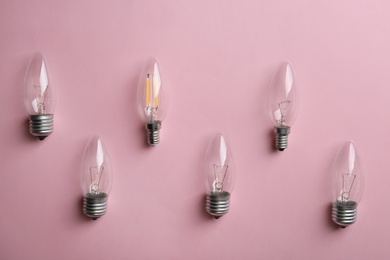 Vintage and modern lamp bulbs on pink background, flat lay