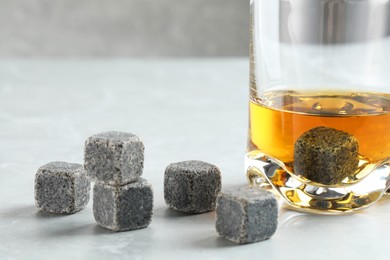 Photo of Whiskey stones and drink in glass on light table, closeup