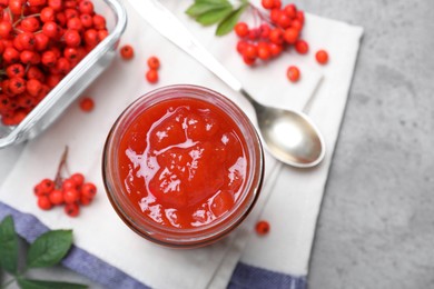 Flat lay composition with delicious rowan jam on grey table. Space for text