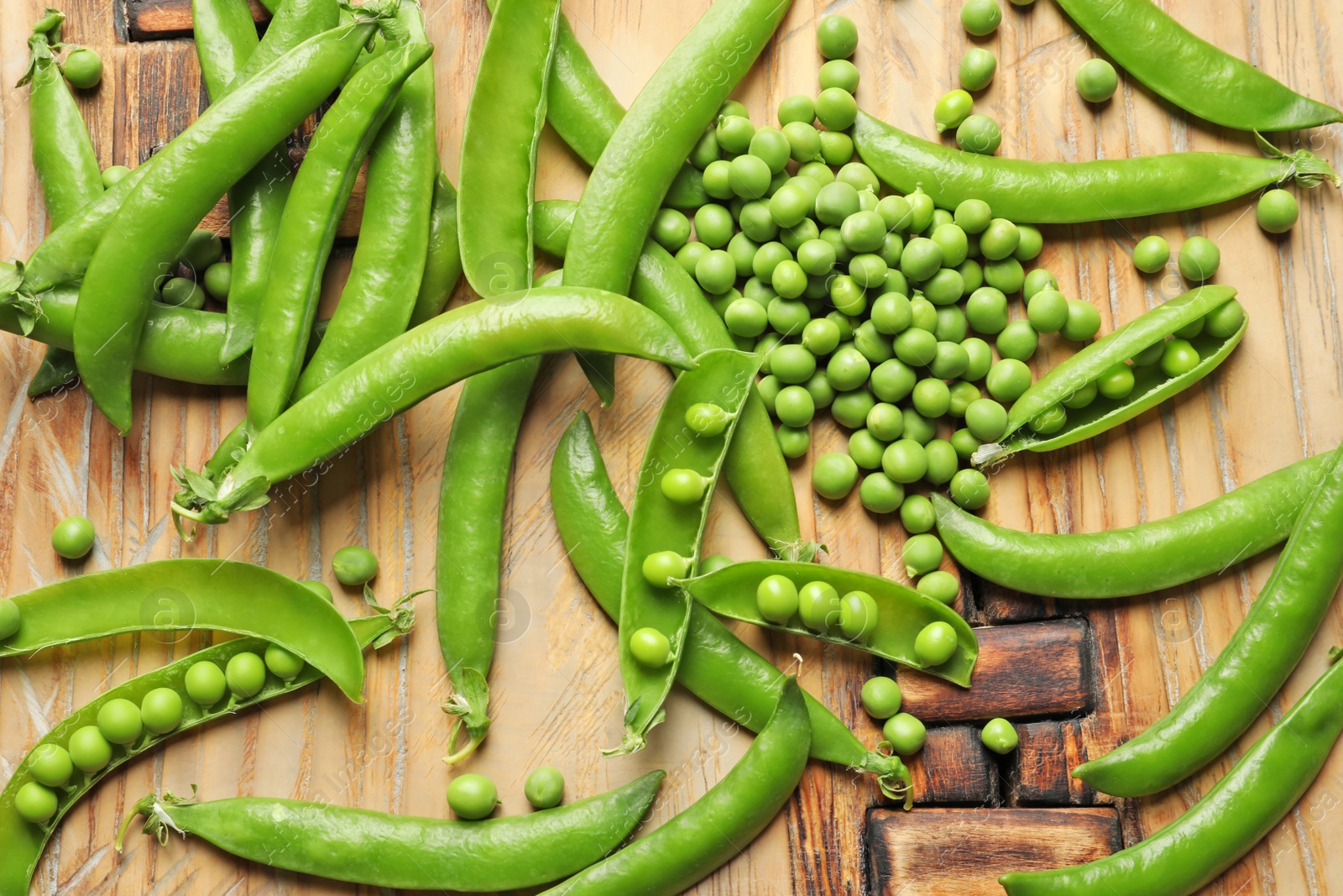 Photo of Fresh green peas on wooden background, top view