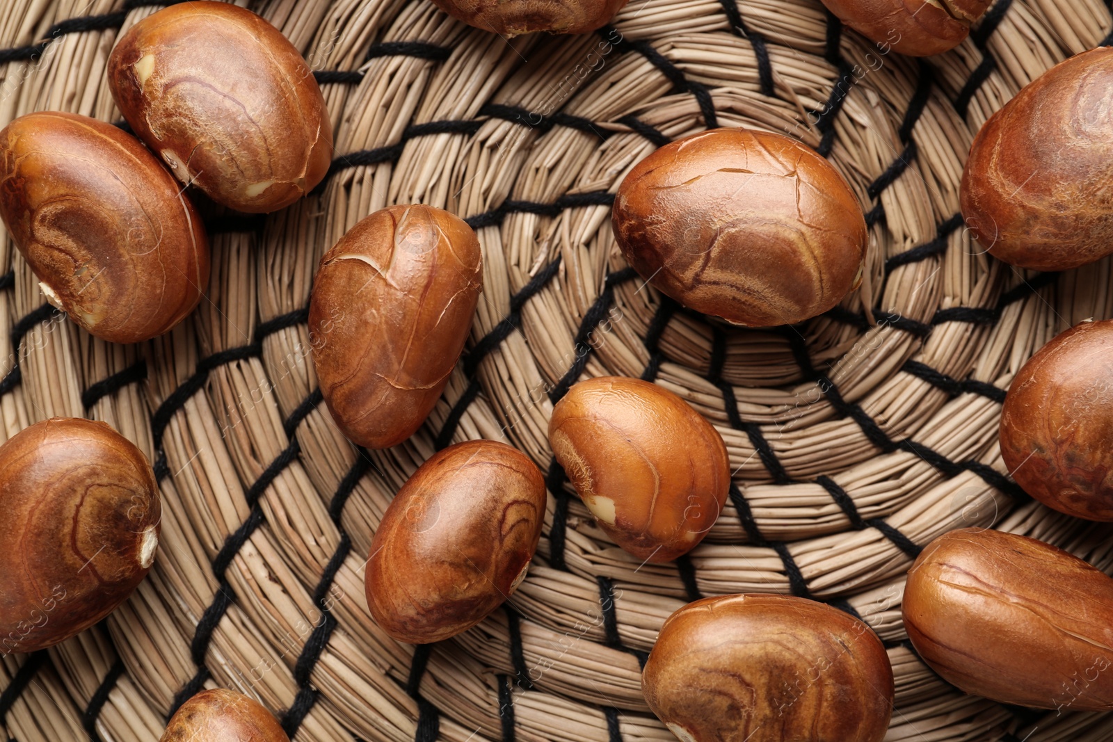 Photo of Many raw jackfruit seeds on wicker mat, flat lay