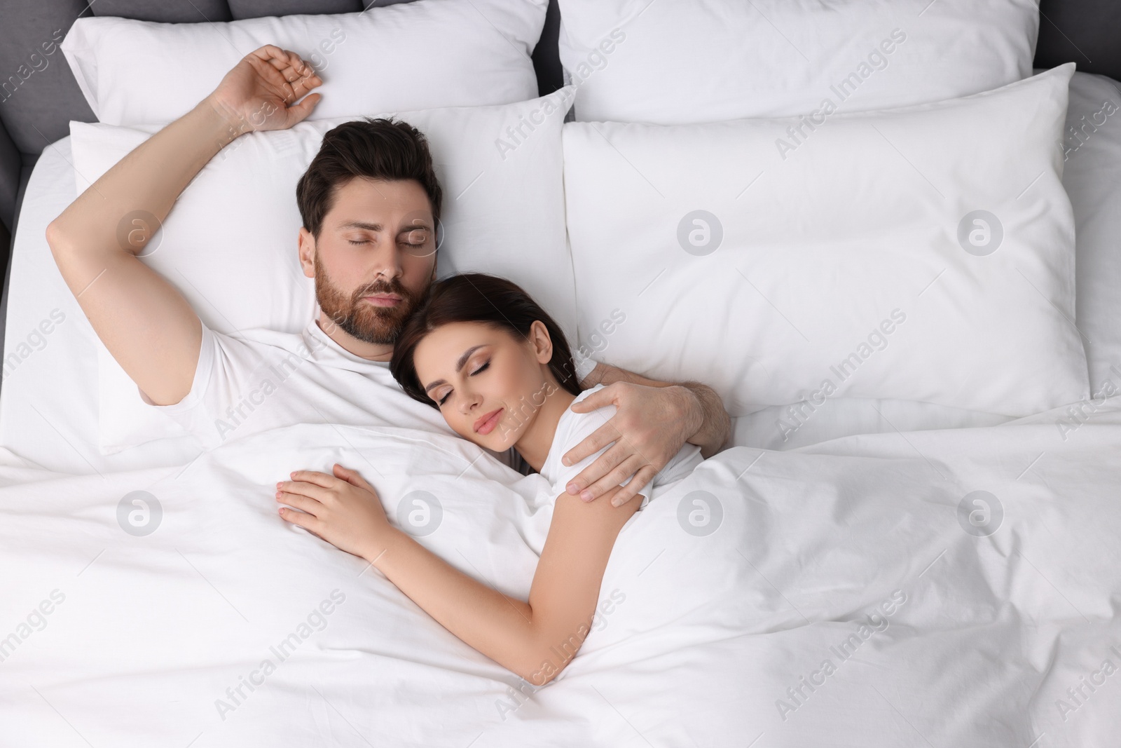 Photo of Lovely couple sleeping together in bed at home, top view