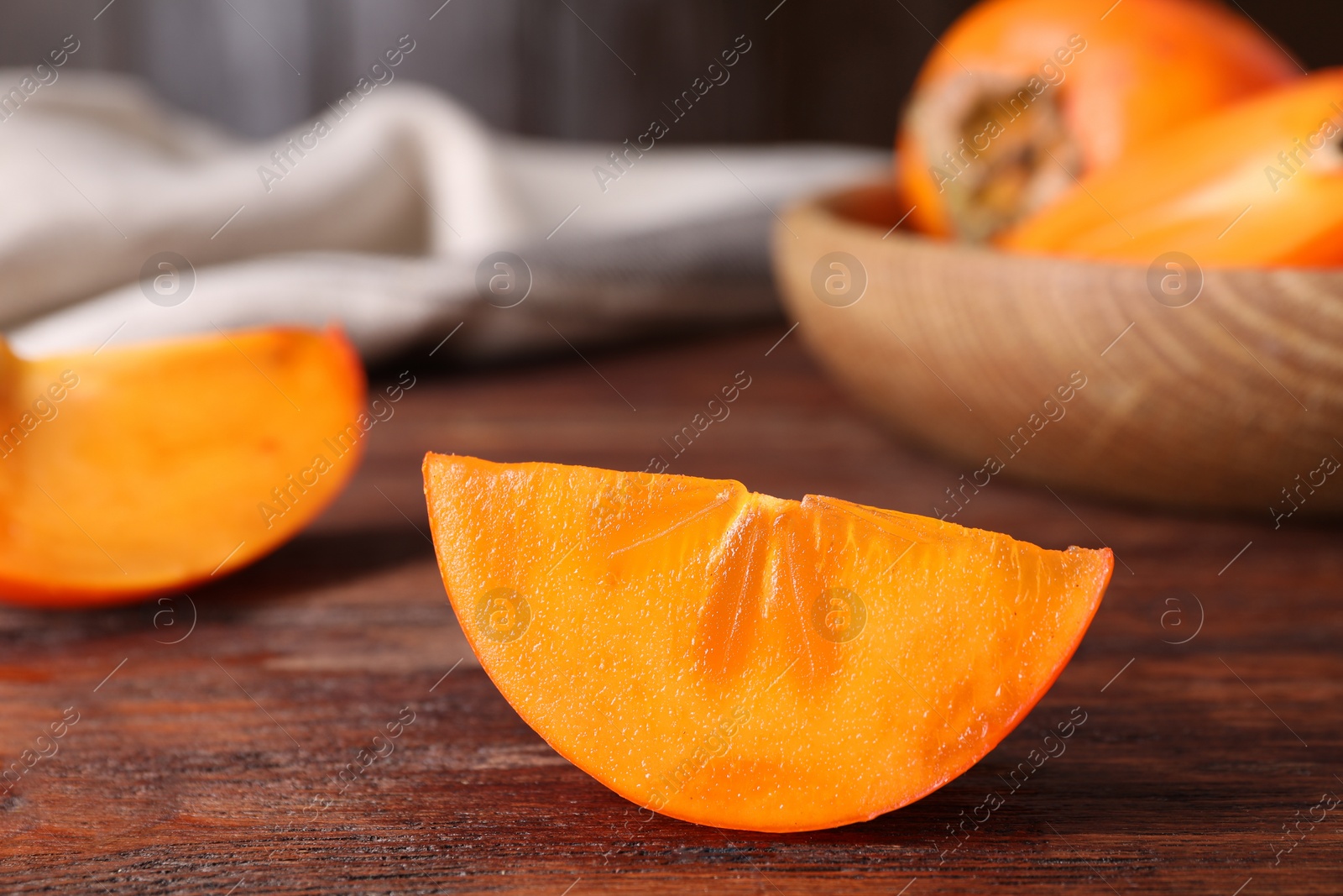 Photo of Piece of delicious ripe persimmon on wooden table, closeup