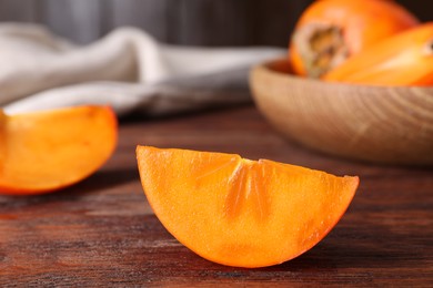 Piece of delicious ripe persimmon on wooden table, closeup