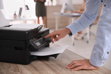 Photo of Employee using modern printer in office, closeup