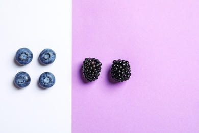 Photo of Flat lay composition with blackberries and blueberries on color background