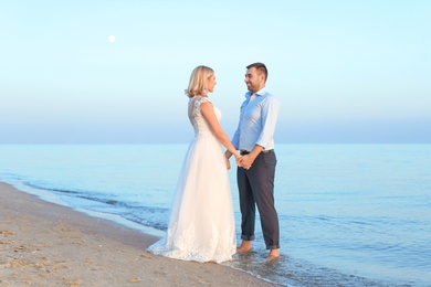 Wedding couple holding hands together on beach