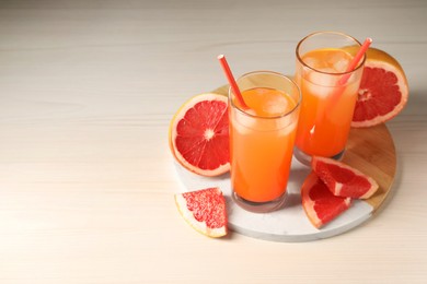 Photo of Tasty freshly made grapefruit juice and fruits on white wooden table, space for text