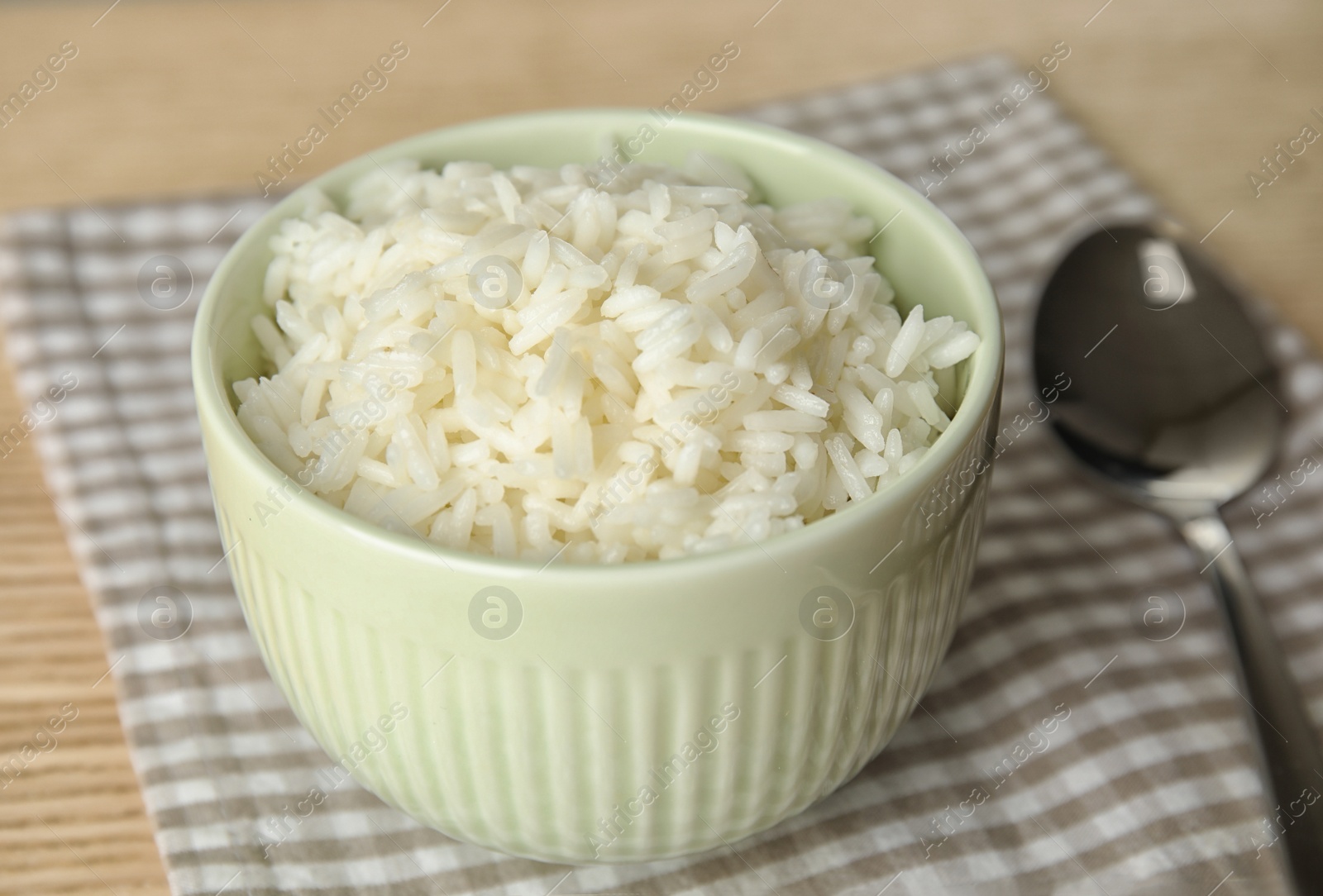 Photo of Bowl with tasty cooked rice on wooden table, closeup