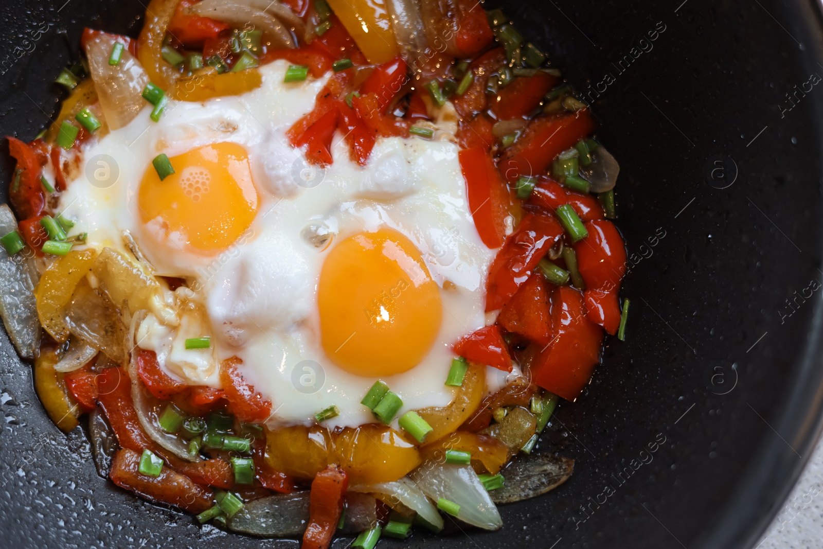 Photo of Cooking tasty eggs with vegetables in frying pan, closeup