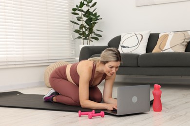 Photo of Online fitness trainer. Woman watching tutorial on laptop at home