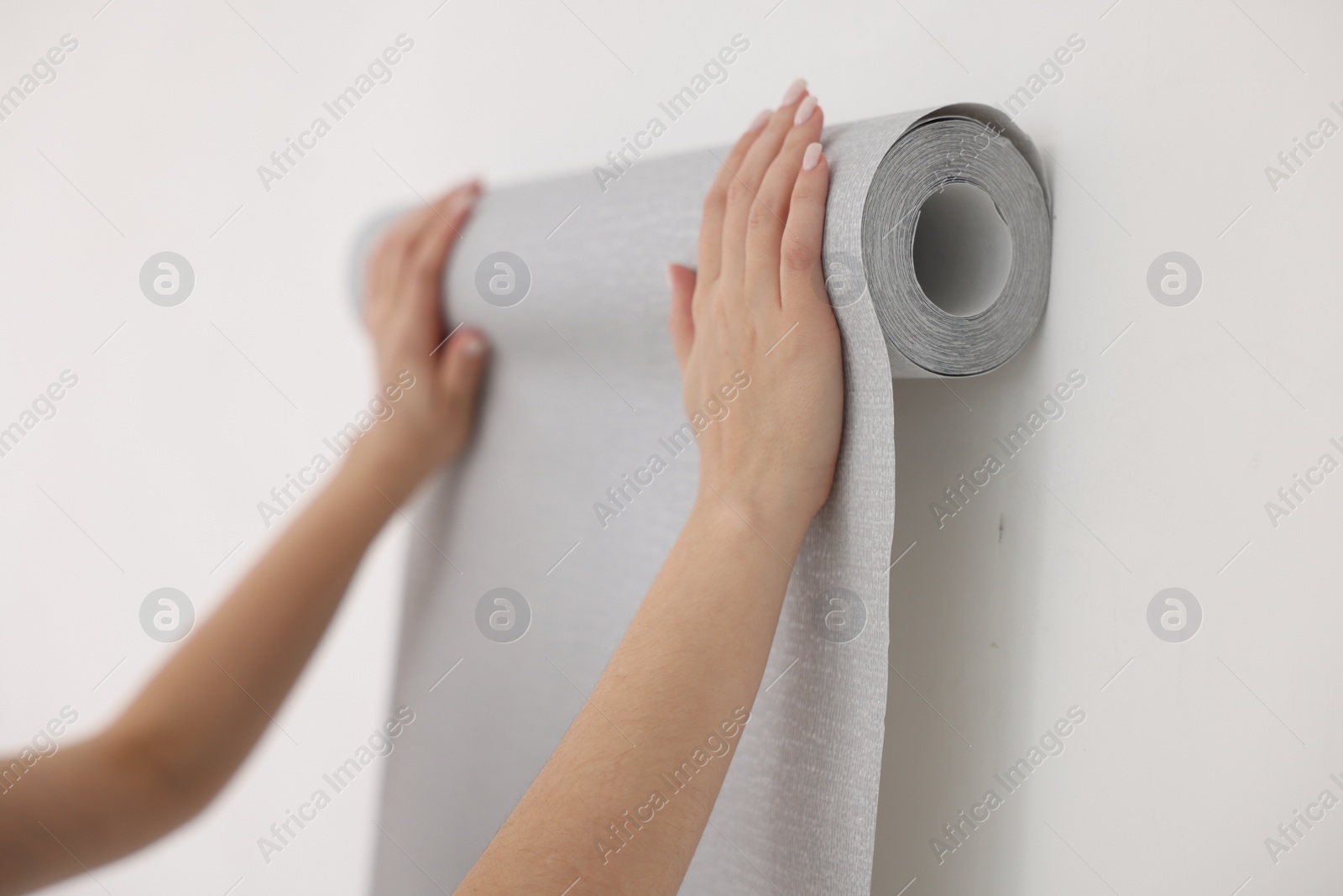 Photo of Woman hanging gray wallpaper in room, closeup