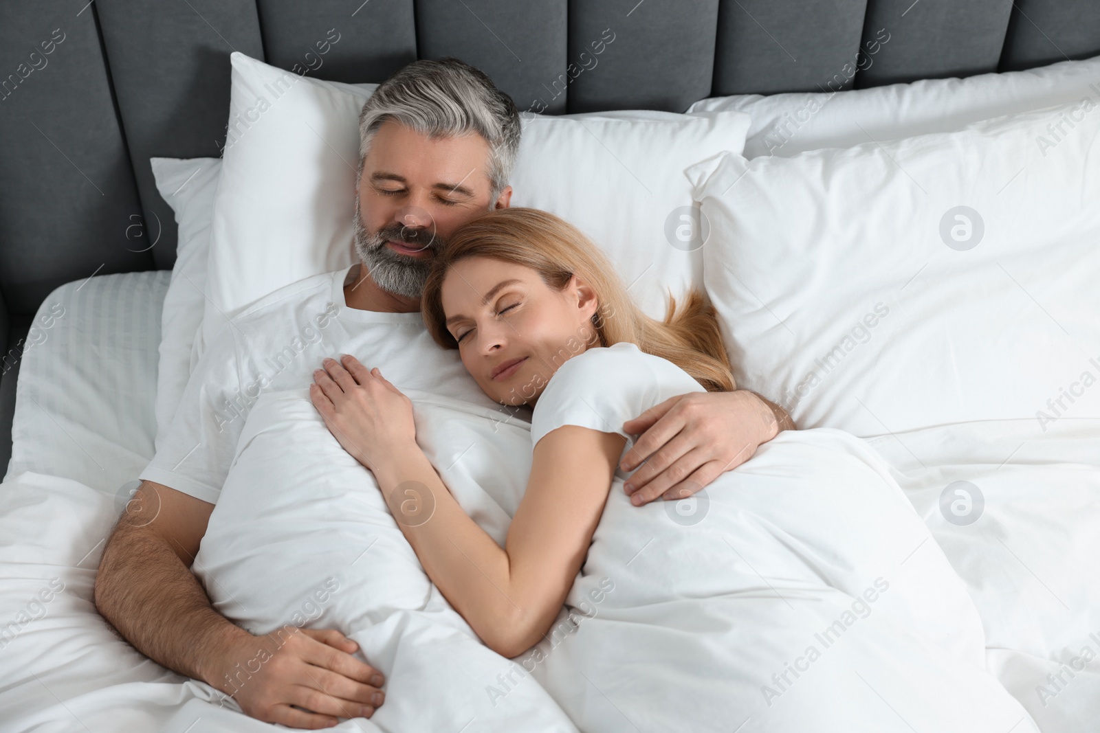 Photo of Lovely mature couple sleeping together in bed at home, above view