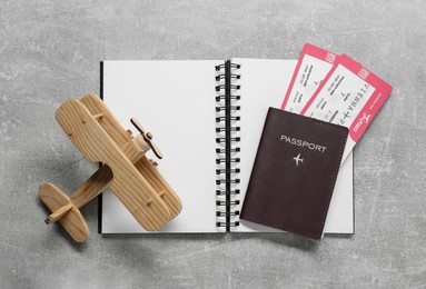 Photo of Flat lay composition with tickets, passport and wooden model of plane on light grey table. Business trip