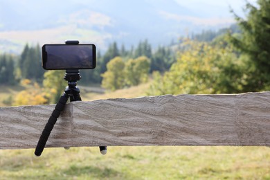 Tripod with smartphone outdoors. Space for text