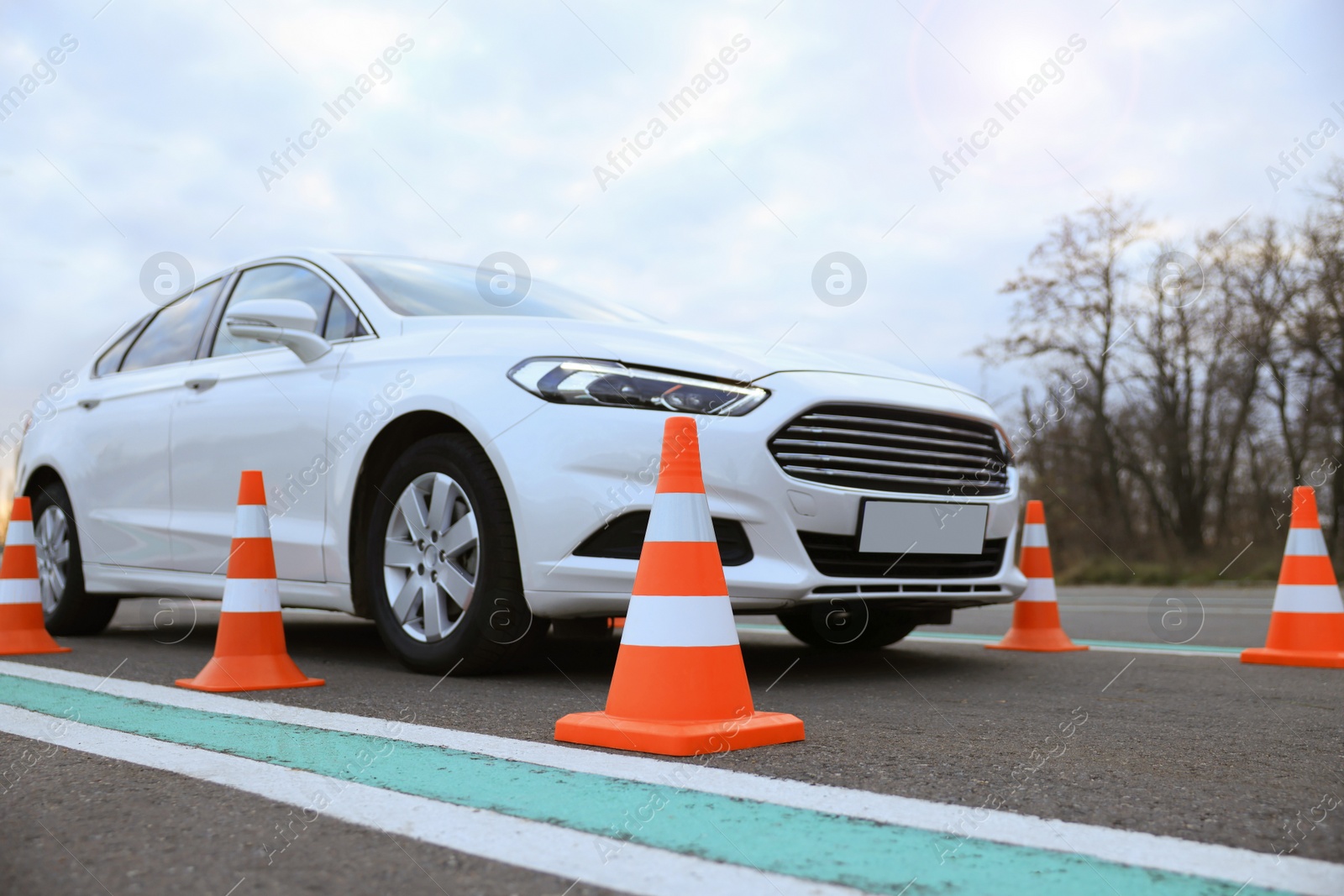 Photo of Modern car on test track with traffic cones, low angle view. Driving school