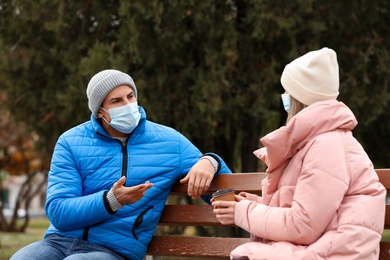 Photo of People in medical masks keeping distance while talking outdoors. Protective measures during coronavirus quarantine