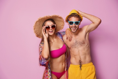 Happy young couple in beachwear on color background