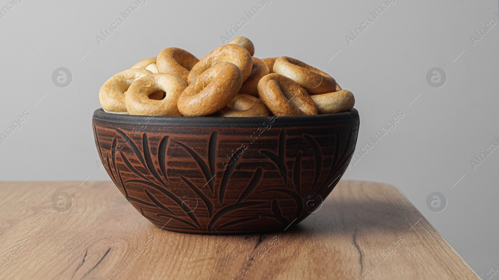 Photo of Bowl of tasty dry bagels (sushki) on wooden table