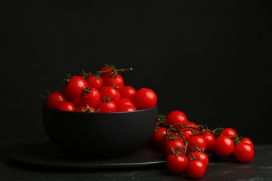 Fresh ripe cherry tomatoes with water drops on black table