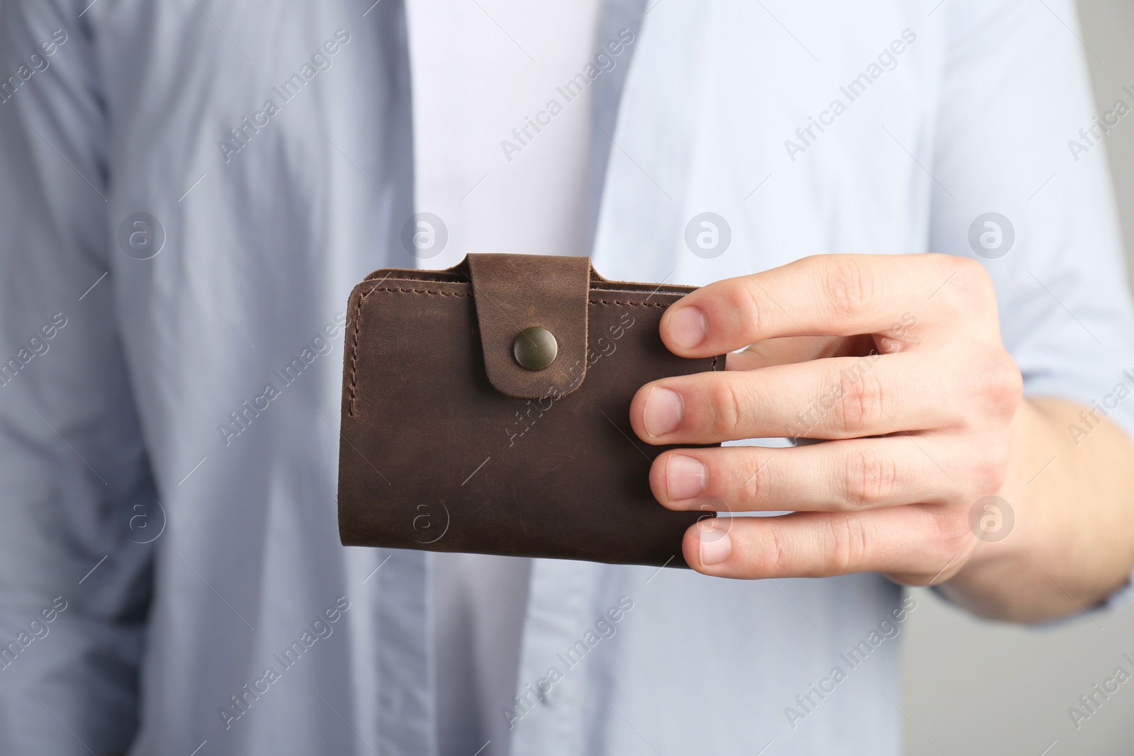 Photo of Man holding leather business card holder on grey background, closeup