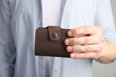 Man holding leather business card holder on grey background, closeup