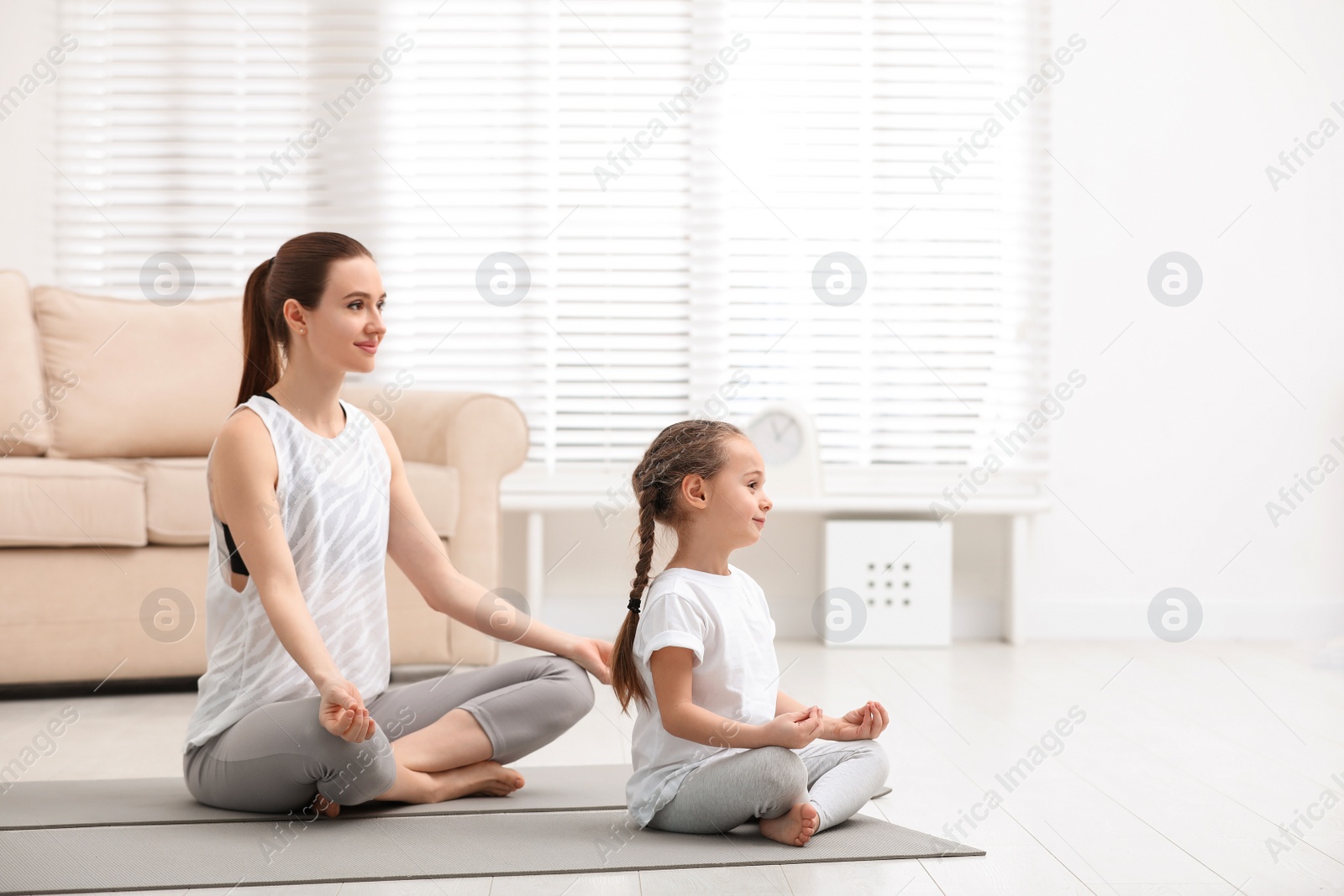 Photo of Young mother with little daughter practicing yoga at home