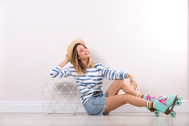 Photo of Young woman with retro roller skates near white wall