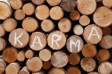 Photo of Many firewood with word Karma as background, closeup