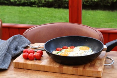 Delicious fried eggs with tomatoes and pepper served on wooden table