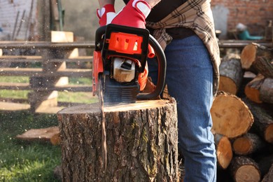 Photo of Man sawing wooden log on sunny day, closeup