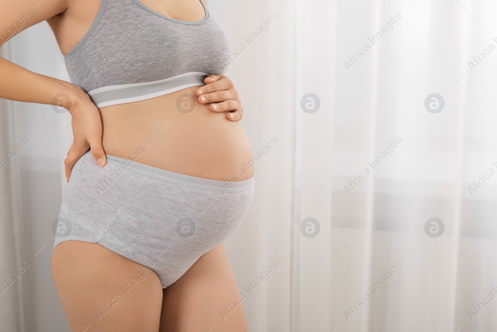Photo of Pregnant woman in comfortable maternity underwear indoors, closeup. Space for text