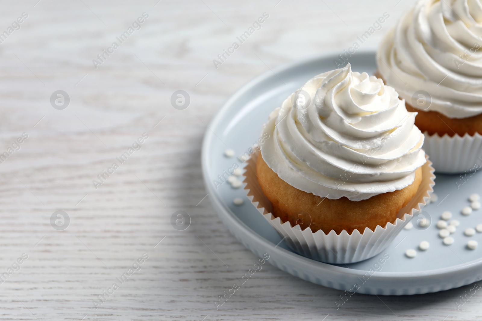 Photo of Delicious cupcakes with cream on white wooden table, closeup. Space for text