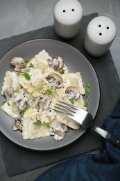 Photo of Delicious ravioli with tasty sauce and mushrooms served on black table, flat lay