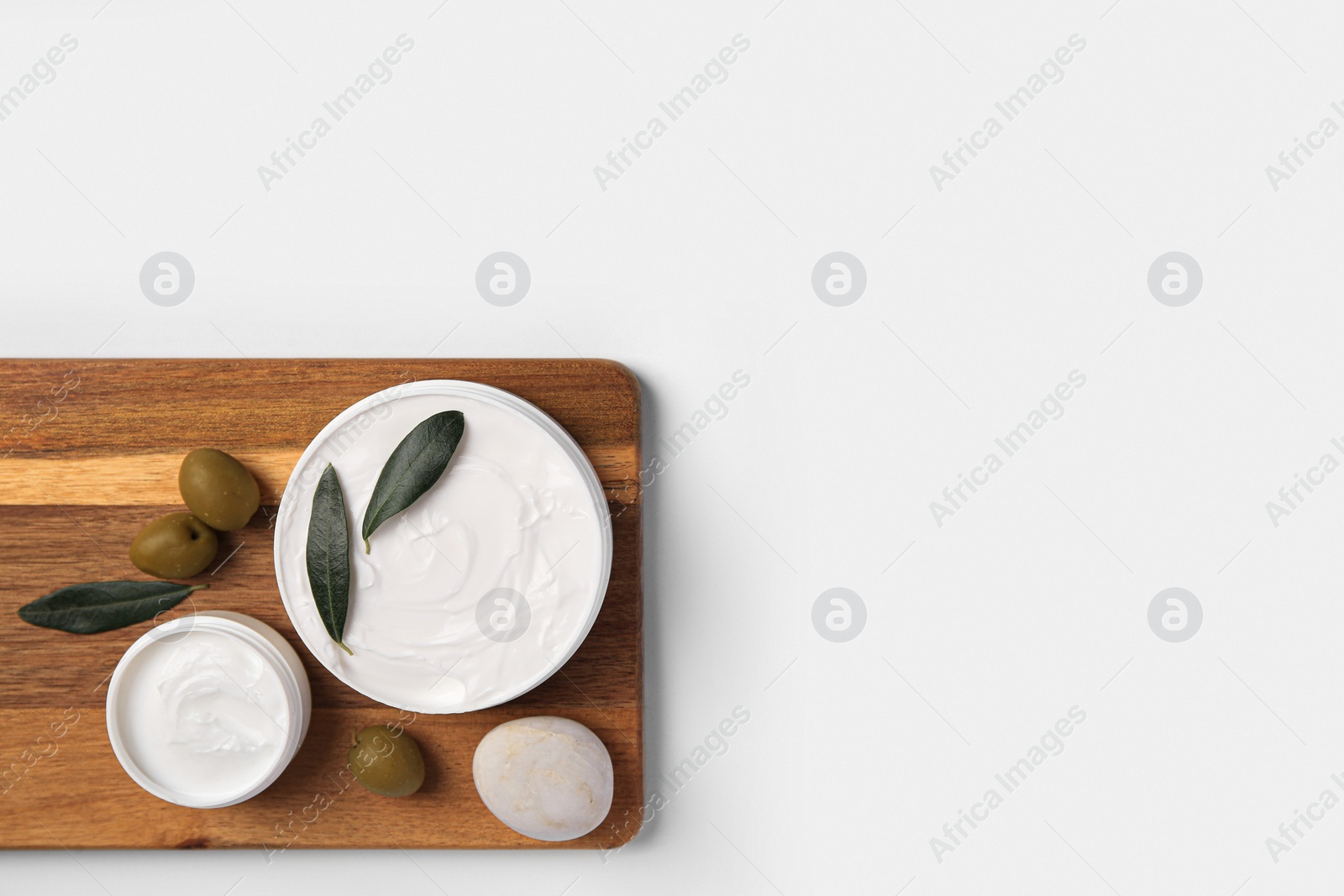 Photo of Jars of cream with olives and stone on white background, top view. Space for text