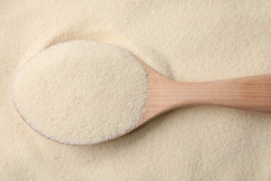 Photo of Uncooked organic semolina and wooden spoon, top view