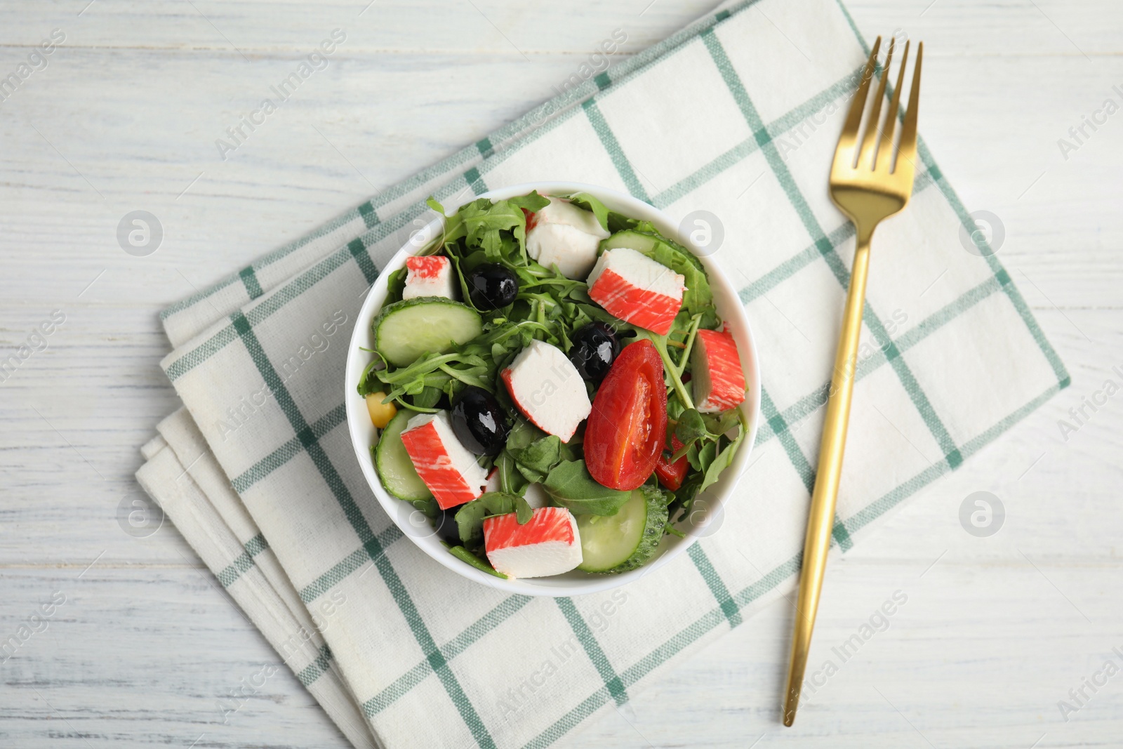 Photo of Tasty crab stick salad served on white wooden table, flat lay