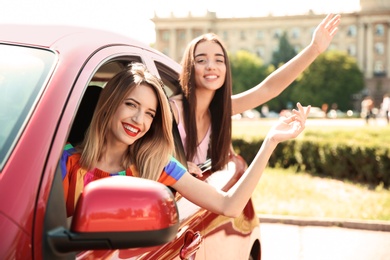 Young women in car outdoors on sunny day
