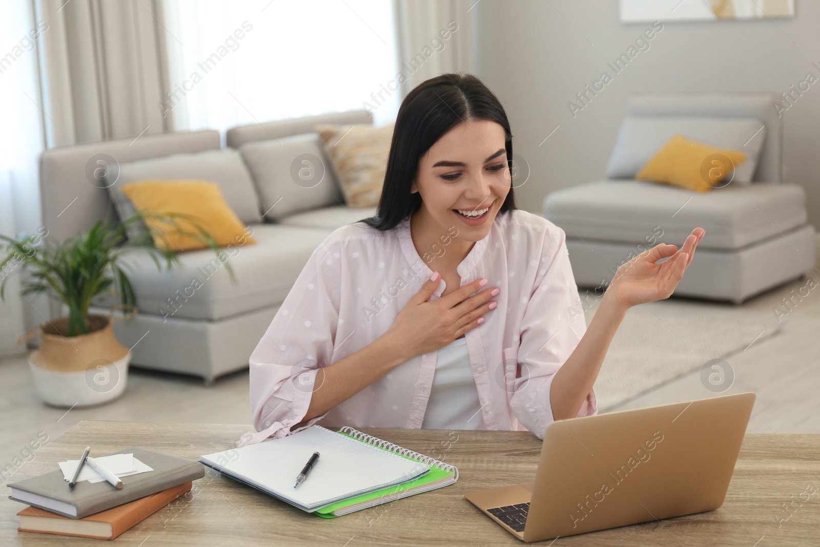 Photo of Young woman watching online webinar at table indoors